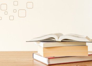 a stack of four books with the top book opened
