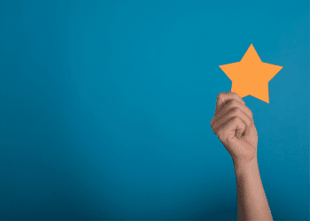 Blue background with a hand holding up a yellow 5 pointed star cutout