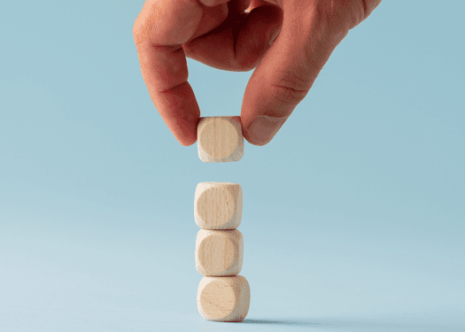 A hand stacking 4 tiny wooden blocks