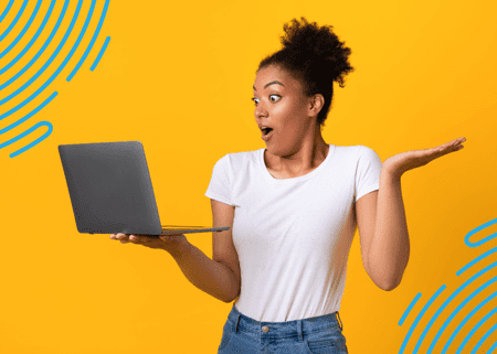 Woman holding laptop in left hand with a shocked look on her face