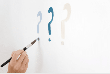a hand painting question marks on a wall