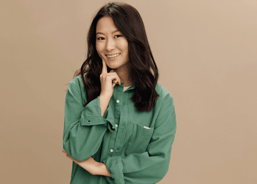 A woman in a green shirt smiling with an inquisitive look.